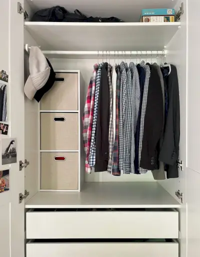 Armoire penderie Ikea Pax ouverte avec des chemises pour hommes sur une tringle suspendue