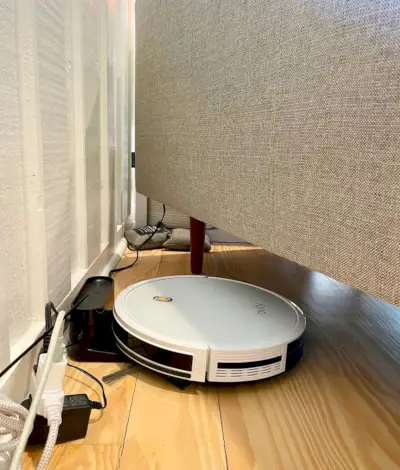 Eufy RoboVac 11S carregant a l'estació base connectada sota el sofà