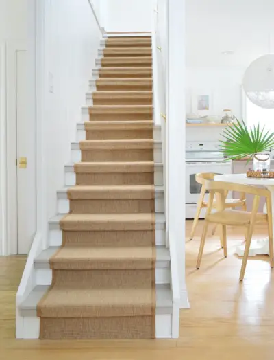 Finition du chemin d'escalier en sisal sur l'escalier avec cuisine en arrière-plan