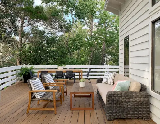 Sitzbereich auf dem Deck mit Couchtisch im Freien und zwei geflochtenen Liegestühlen