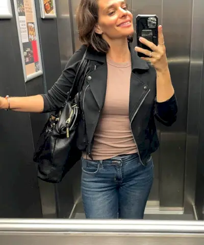 Sherry selfie dans l'ascenseur avec débardeur beige, veste en cuir noir et jean