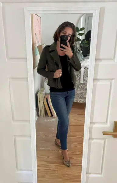 Sherry selfie dans un miroir à la maison avec un débardeur noir, une veste verte et des chaussures plates à imprimé léopard