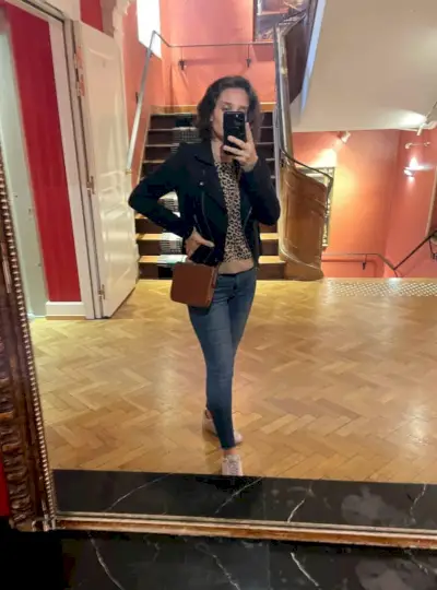 Sherry selfie dans le miroir de l'hôtel avec un pull léopard sous une veste noire et des chaussures de tennis