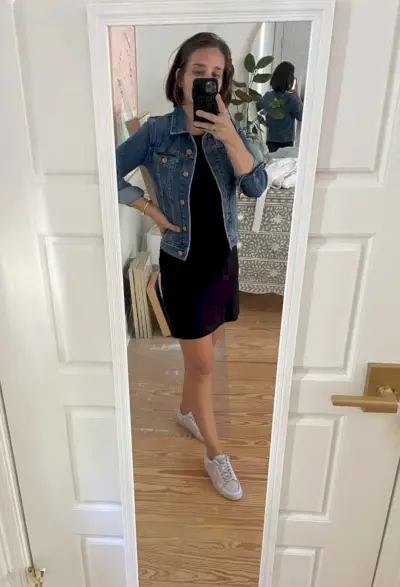 Sherry selfie dans le miroir à la maison avec une robe noire courte sous une veste en jean avec des chaussures de tennis