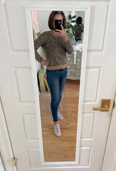 Sherry selfie no espelho em casa com suéter leopardo e jeans