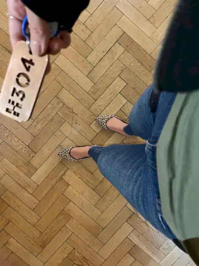 Prise de vue d'en haut sur des jeans et des chaussures plates léopard sur un parquet à chevrons