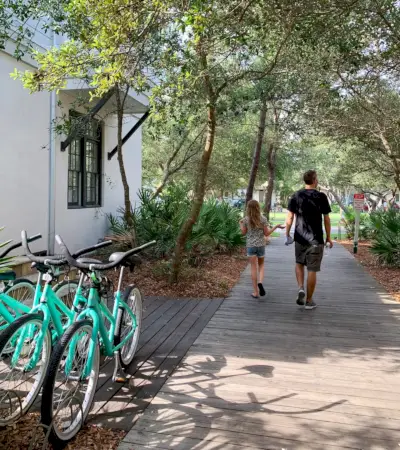 John et sa fille marchant sur une allée boisée à côté de vélos