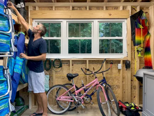 John cherche quelque chose dans le hangar d'une maison de plage.