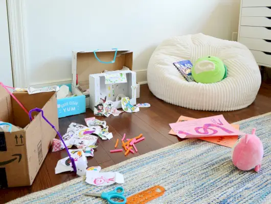 Bambini che creano scatole da gioco in cartone sul pavimento della sala d'arte con un sacchetto di fagioli