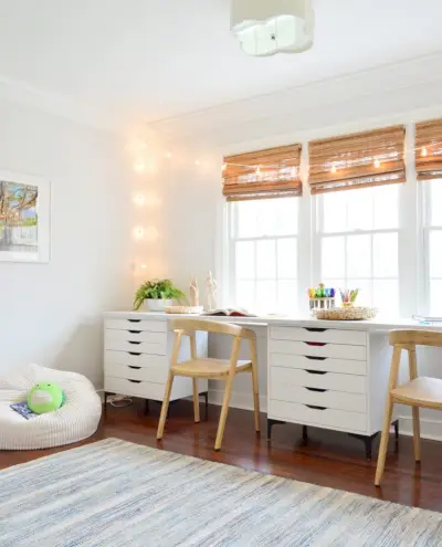 Salle d'art pour enfants avec deux chaises en bois le long d'un long espace de travail avec guirlande lumineuse