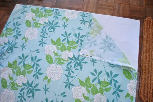 comment une doublure en tissu occultant abordable est superposée derrière un tissu floral coloré pour créer des rideaux occultants DIY