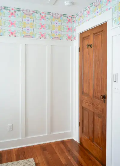 Porta de madeira na sala com quadro branco e sarrafo e papel de parede colorido de casca e bastão