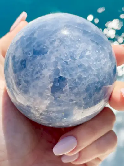 Sphère de cristal de calcite bleue au-dessus de l'eau