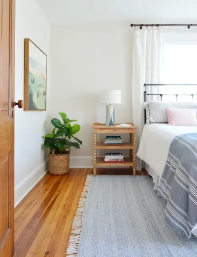 Dormitorio frente a la casa de playa con alfombra azul y mesita de noche de madera