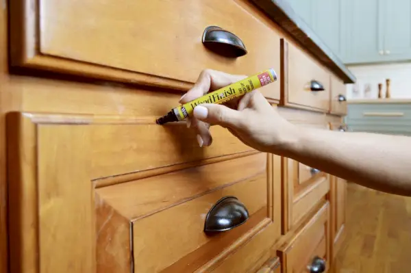 Sherry applique un marqueur de teinture sur des armoires en bois