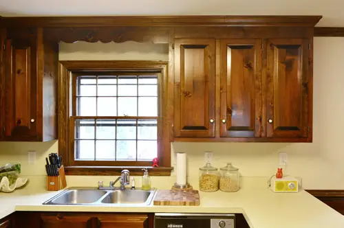 Foto anterior de una cocina de los años 80 con gabinetes de pared de madera oscura.