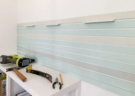 Première section de bandes de treillis en bois peint fixées au mur à l'aide d'entretoises