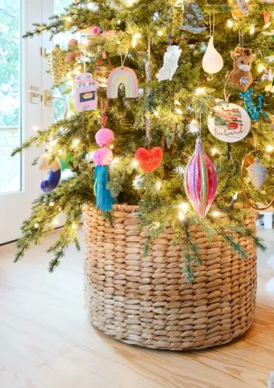 Geflochtener Korb am Fuß des Weihnachtsbaums mit bunten Ornamenten