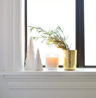 Arbres en céramique blanche avec bougie et vase doré sur le rebord de la fenêtre de la salle de bains