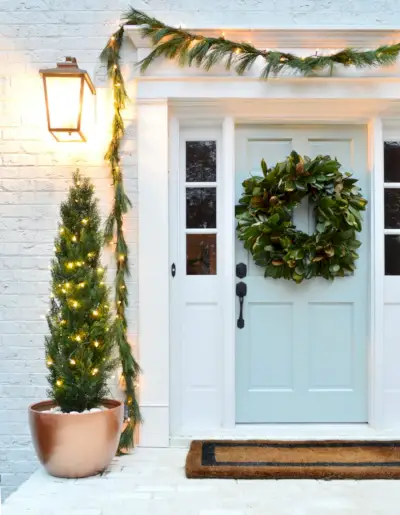 Primo piano del portico anteriore con porta dipinta di blu decorata per Natale