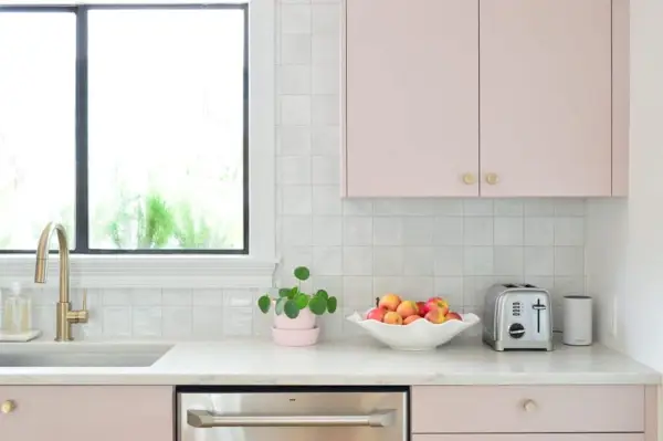 Vista più ravvicinata del backsplash di piastrelle quadrate con armadi verniciati rosa malva