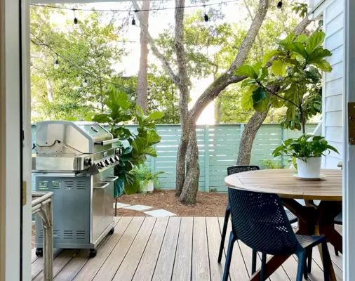 Vista del porche de la cocina a través de la puerta con árboles y valla