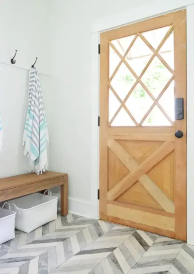 Porta de madeira com painéis de diamante com banco e ganchos em mudroom duplex