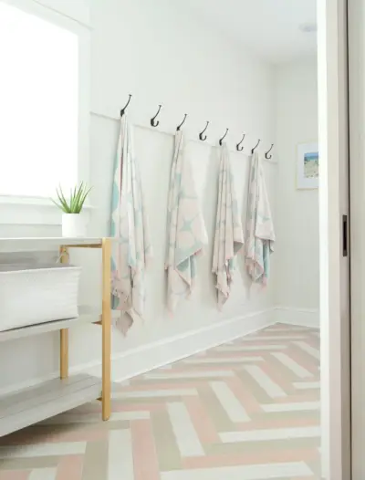 Rangement de crochets pour serviettes suspendus dans un vestiaire duplex avec sols en carrelage à chevrons