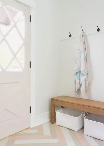 Trilho de gancho de toalha com porta rosa diamante em mudroom duplex com banco