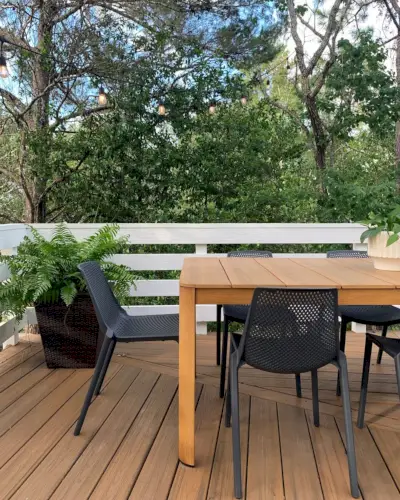 Vista de cerca de una mesa de madera sintética de metal con sillas de plástico negro