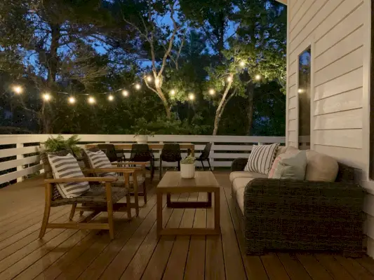 Vue nocturne du coin salon sur la terrasse extérieure avec guirlandes lumineuses