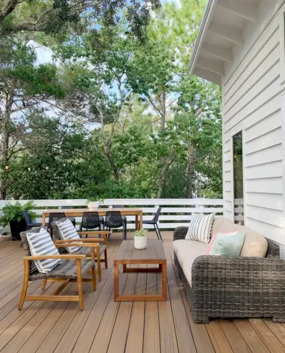 Sitzbereich auf dem Deck mit Couchtisch im Freien und zwei geflochtenen Liegestühlen