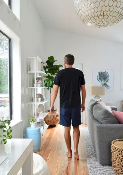 Homme En Chemise Noire Marchant Dans Le Salon Sous Un Grand Luminaire