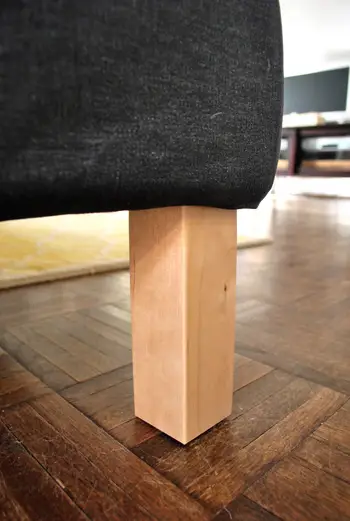 Detalle de primer plano de las patas del sofá seccional de Ikea en madera rubia sin terminar