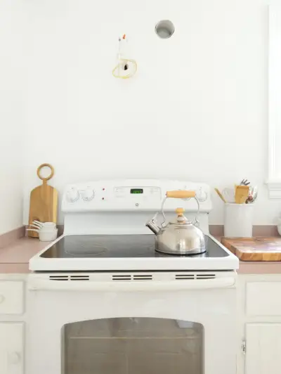 Espace mural vide au-dessus d'une cuisinière blanche dans une cuisine blanche minimale