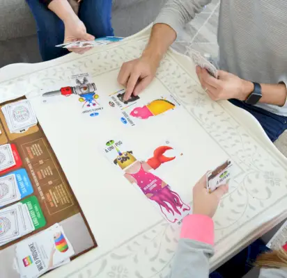 Manos jugando al juego de mesa osos vs bebés en una mesa de café estarcida