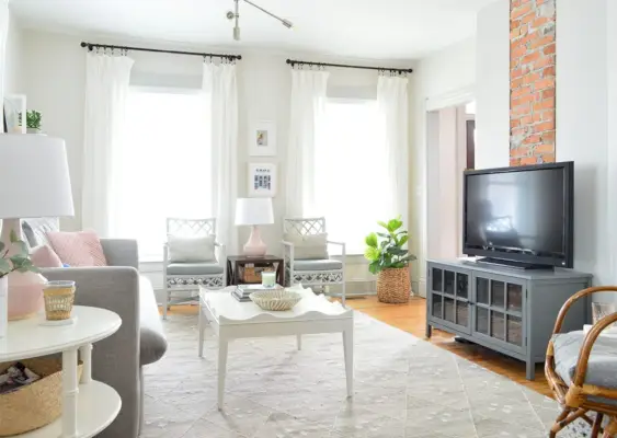 TV en un luminoso salón gris neutro contra una chimenea de ladrillo visto