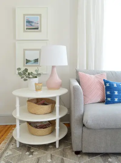 table d'appoint ronde en bambou blanc à trois niveaux avec lampe rose et canapé gris