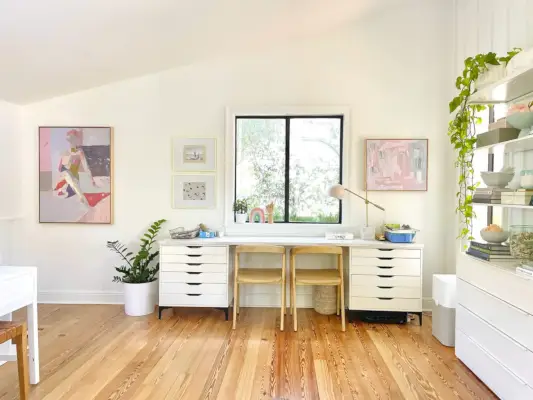 Bureau d'art pour enfants sous la fenêtre dans une salle familiale blanche moderne ouverte avec des plafonds défectueux et des œuvres d'art