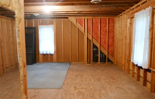 Salle de stockage mansardée inachevée avec colombages apparents et fenêtres à rideaux