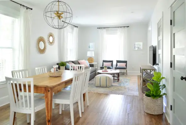 Vista hacia la sala de estar y el comedor abiertos con mesa de madera y lámpara de araña