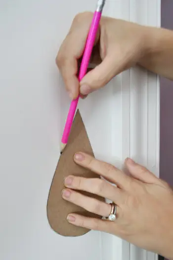 Tracer des gouttes de pluie sur un mur avec un crayon à l'aide d'une forme de gabarit en carton