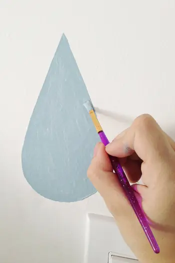 Pintura a mà de la gota de pluja blava al mural amb un pinzell petit