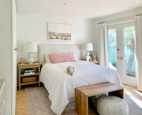 Chambre avec tapis rose avec portes françaises à côté d'un lit blanc