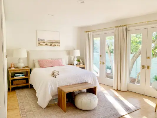 Chambre avec tapis rose avec portes françaises à côté d'un lit blanc