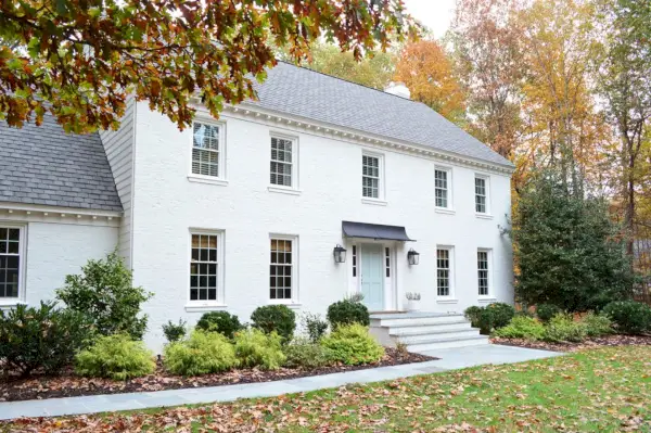 Maison en brique peinte en blanc avec feuilles d'automne