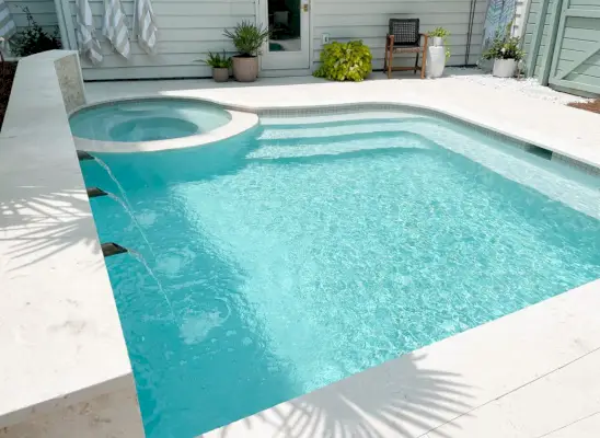 Vista angular de uma pequena piscina de forma livre com escadas em uma extremidade e banco em uma extremidade mostrando gesso Ivory DiamondBrite