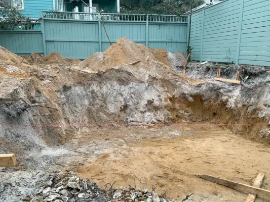 Gran hoyo de tierra cavado en el patio trasero donde se construirá la piscina