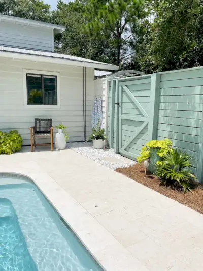 Valla de madera verde gris de listones horizontales alrededor del área de la piscina con puerta cerca de la casa