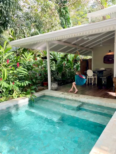 Foto inspiradora de una pequeña piscina tropical junto a la casa blanca y un niño en un columpio